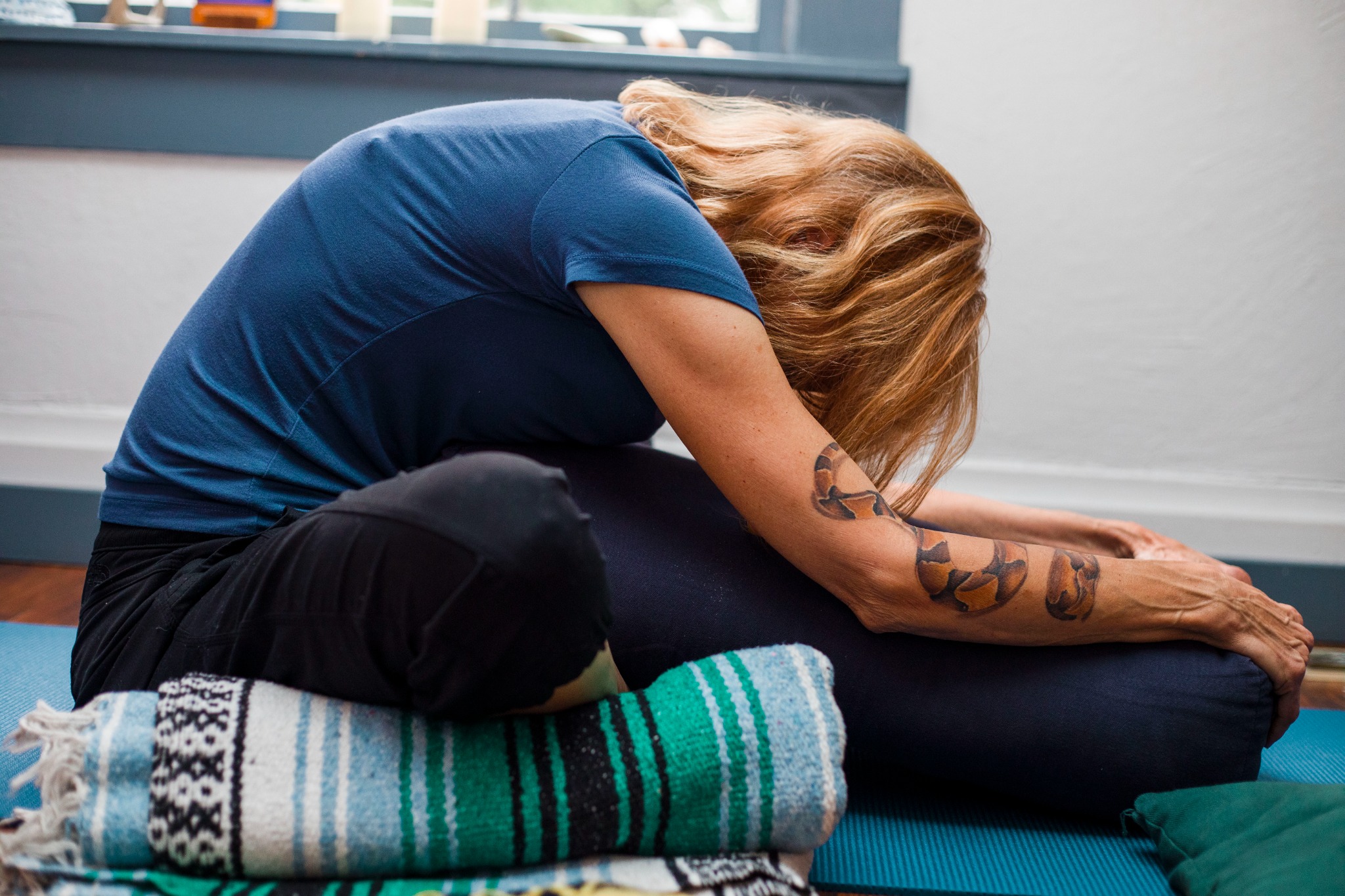 A woman folding forward over a bolster in a supported yin pose